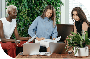 Three professionals with paperwork and computers