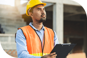 Inspector in orange vest and yellow hat observes with clipboard
