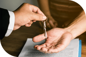 Person handing off house keys to another person over a signed document