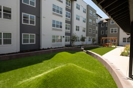 A grassy area between four-story apartment buildings