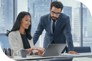 Two professionals in an office review a computer screen