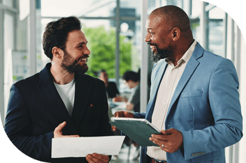 Two professionals smiling at each other over paperwork in the hall