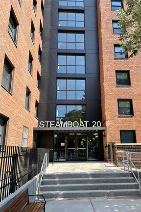 Photo: The front of a tall, red brick building with large windows and letters spelling out "Steamboat 20"