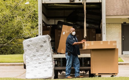 Person unloading mattresses from the back of a moving van