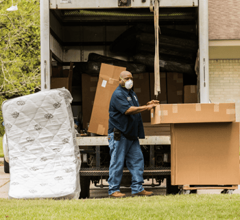 Volunteer unloads a mattress and large boxes from a van