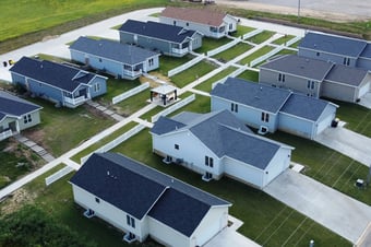 Aerial view of Bear River Cottage Pocket Neighborhood--ten small homes, five on either side of a walkway with a gazebo visible in the center, with lush green lawns