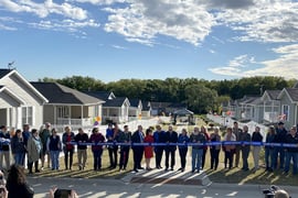 A large crowd gathers in front of the neighborhood for a ribbon cutting
