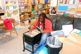 A teenager sorts files in a room full of shelves and boxes