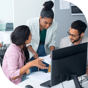 Three professionals gathered around a computer, photo credit kampus-production on pexels