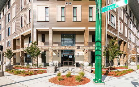 An attractive five-story apartment building with trees and shrubs out front