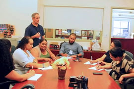 A group of seven takes notes around a conference table